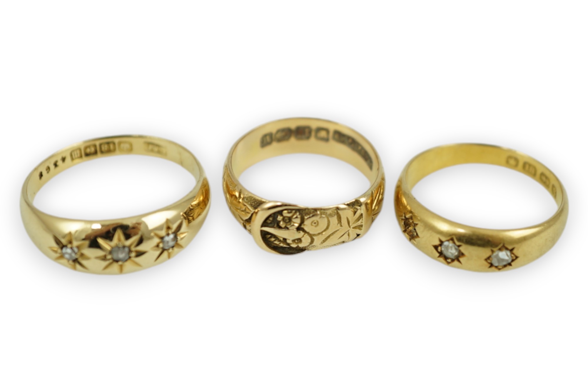 A Victorian 18ct gold buckle ring, size K/L, a Victorian 18ct gold and gypsy set three stone diamond ring (stone missing) and a later 18ct gold and gypsy set three stone diamond ring